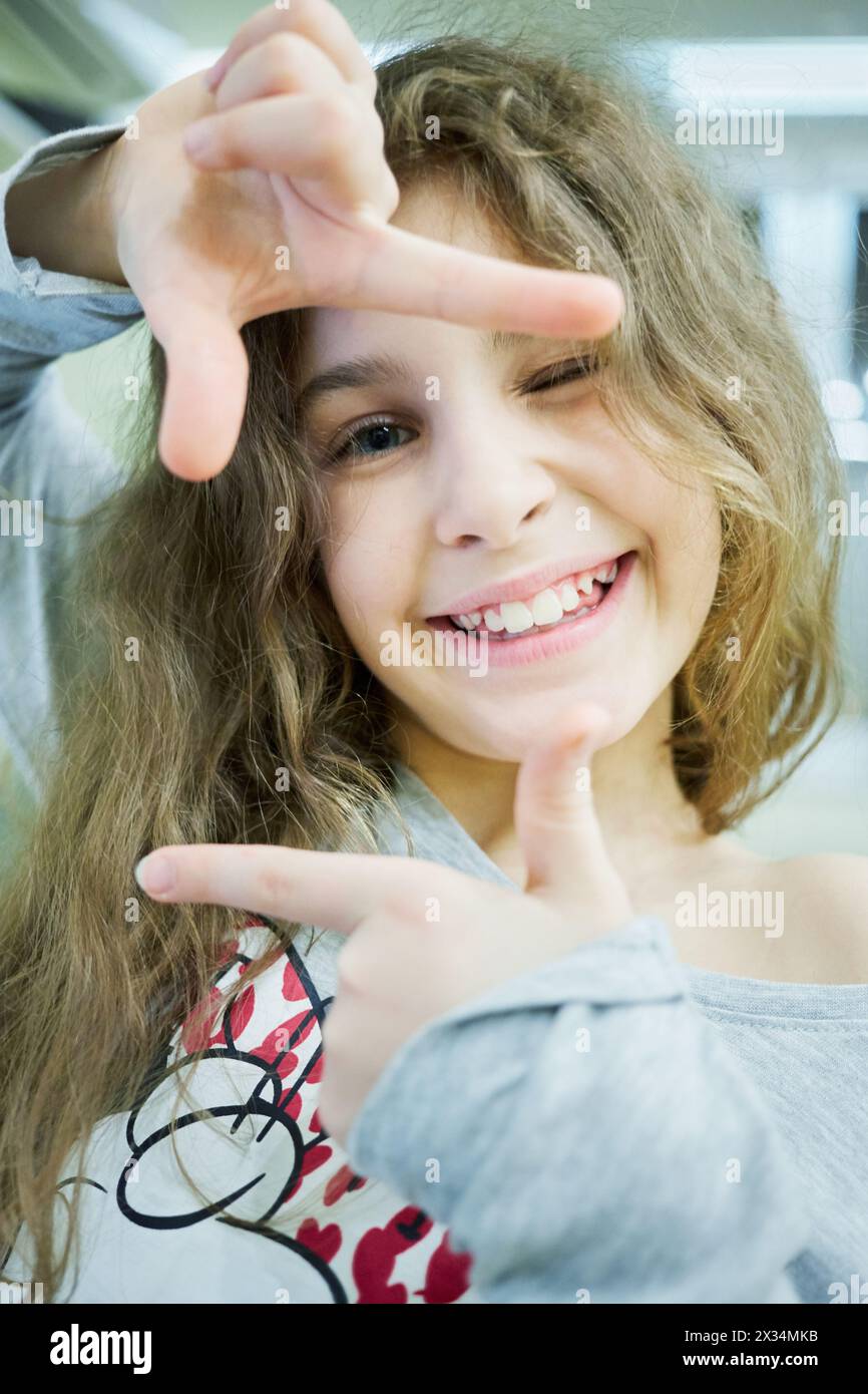 Little smiling girl shows frame with her fingers. Stock Photo