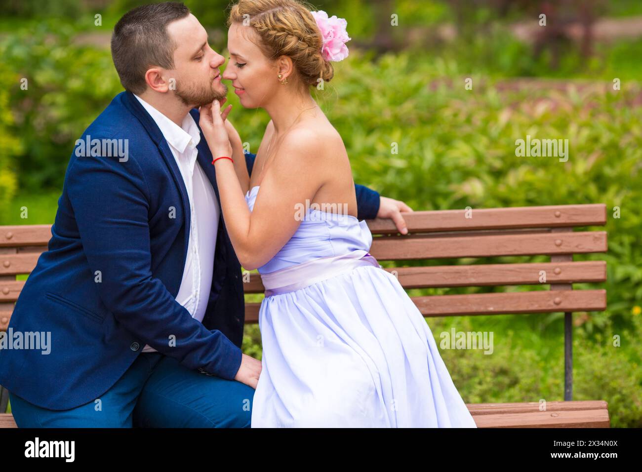 Man and woman embracing and kissing on bench in green summer park Stock ...