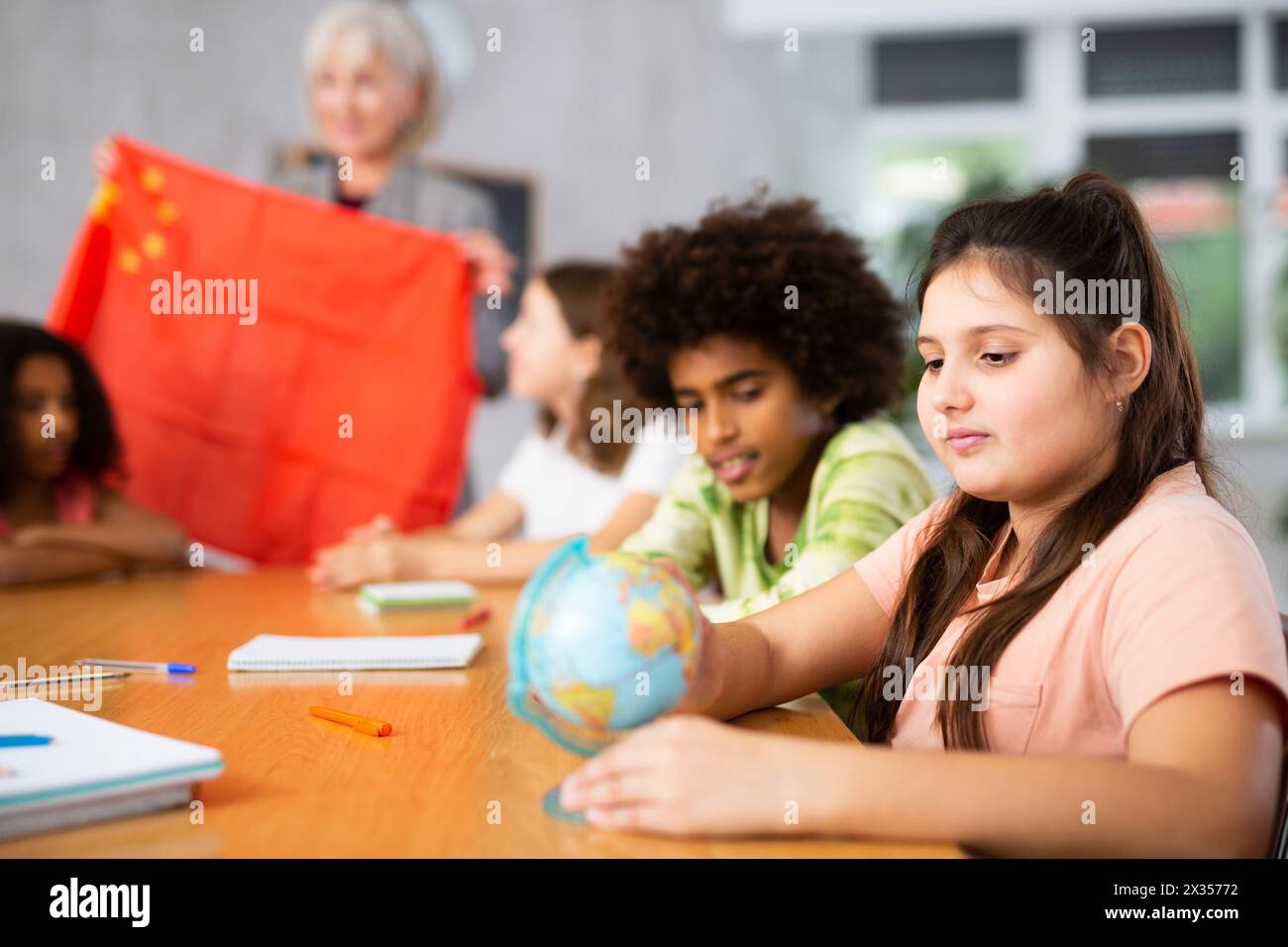 Female teacher showing chinese flag to kids in geography class Stock Photo