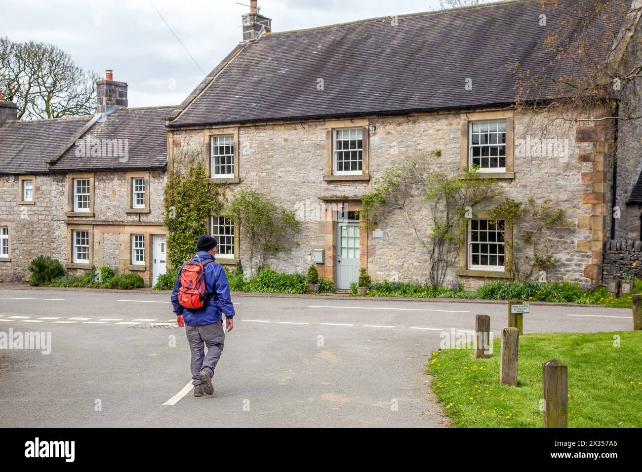 Man walking backpacking rambling through the Peak District village of Alstonefield the Staffordshire Moorlands District of the English Peak District Stock Photo