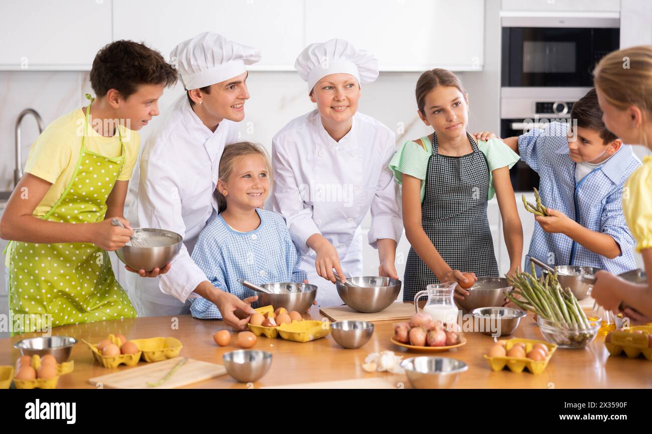 Chef apprentices learn how to properly beat eggs with a whisk in cooking class Stock Photo