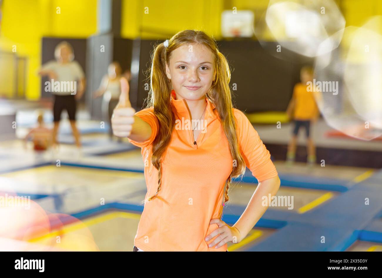 Teenage girl giving thumbs up on trampolines in inflatable amusement ...