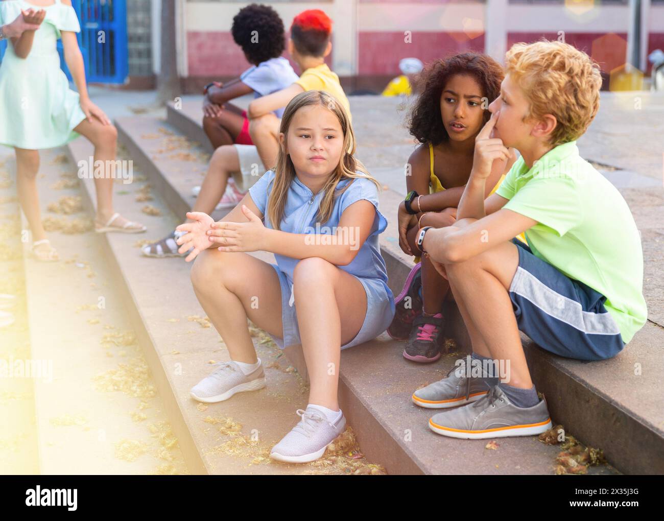 Positive tweenagers friendly blabbing while sitting on steps outdoors Stock Photo