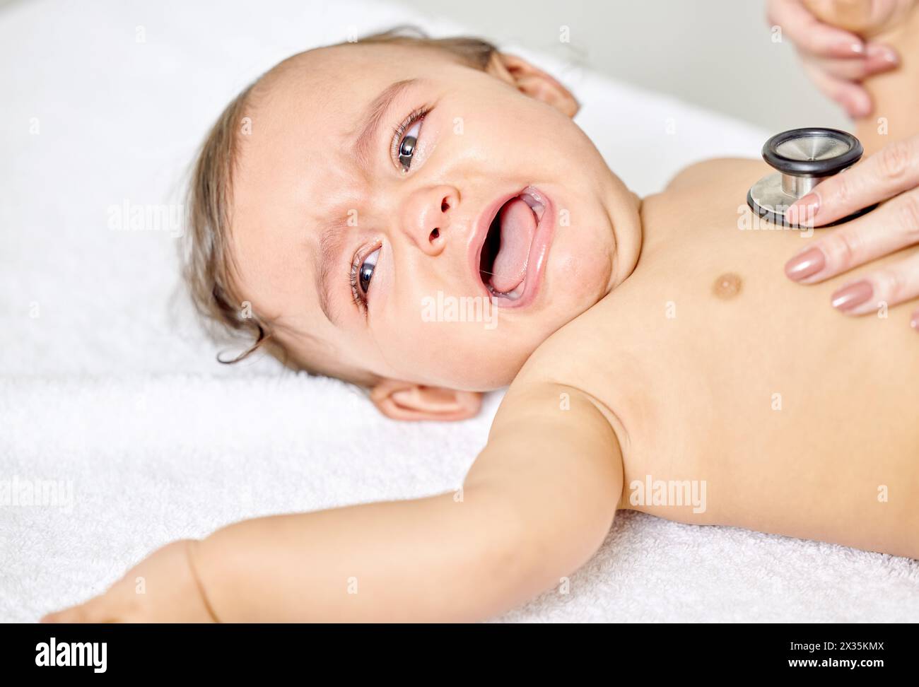 Sick baby, crying and doctor hands with stethoscope for check up, healthcare and stethoscope in heart clinic. Child, female physician and hospital bed Stock Photo