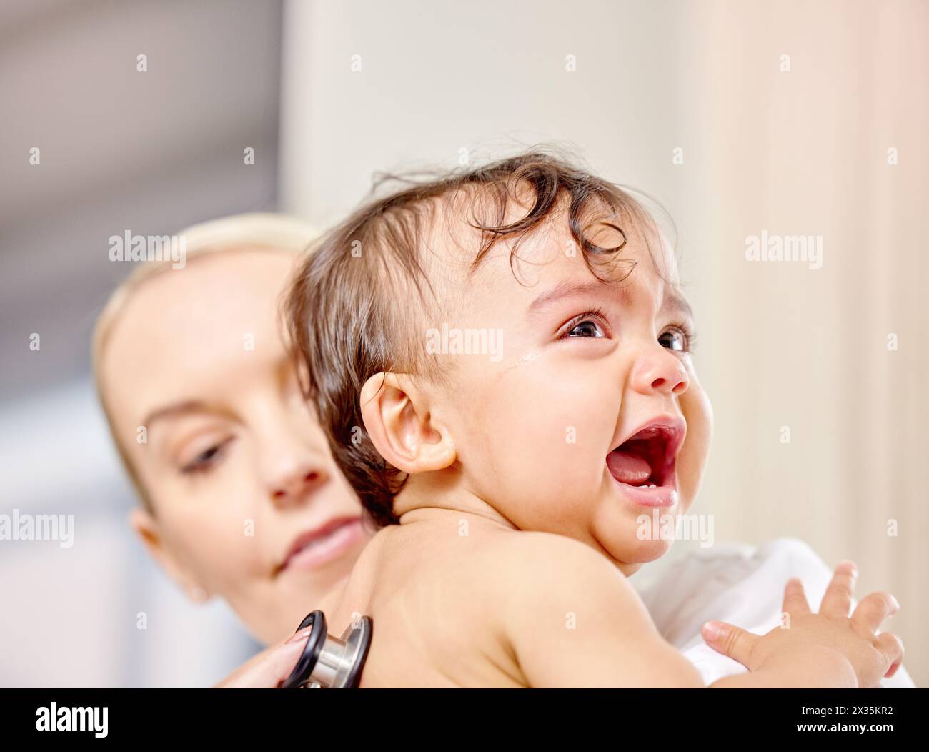 Sick baby, crying and medical woman with stethoscope for check up, healthcare and illness in family clinic. Child, female physician and hospital bed Stock Photo
