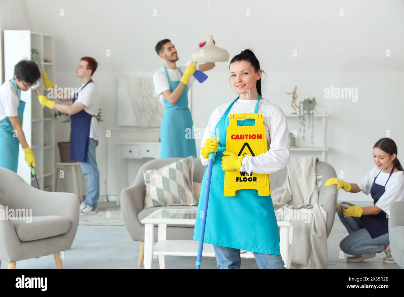 Female janitor with mop and caution sign in room Stock Photo - Alamy