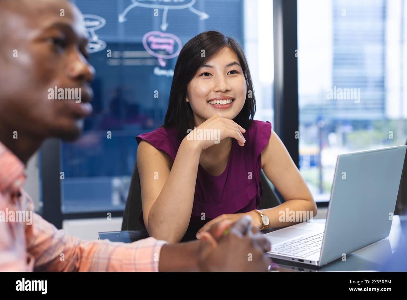 African American man and Asian woman collaborate joyfully in a modern office Stock Photo