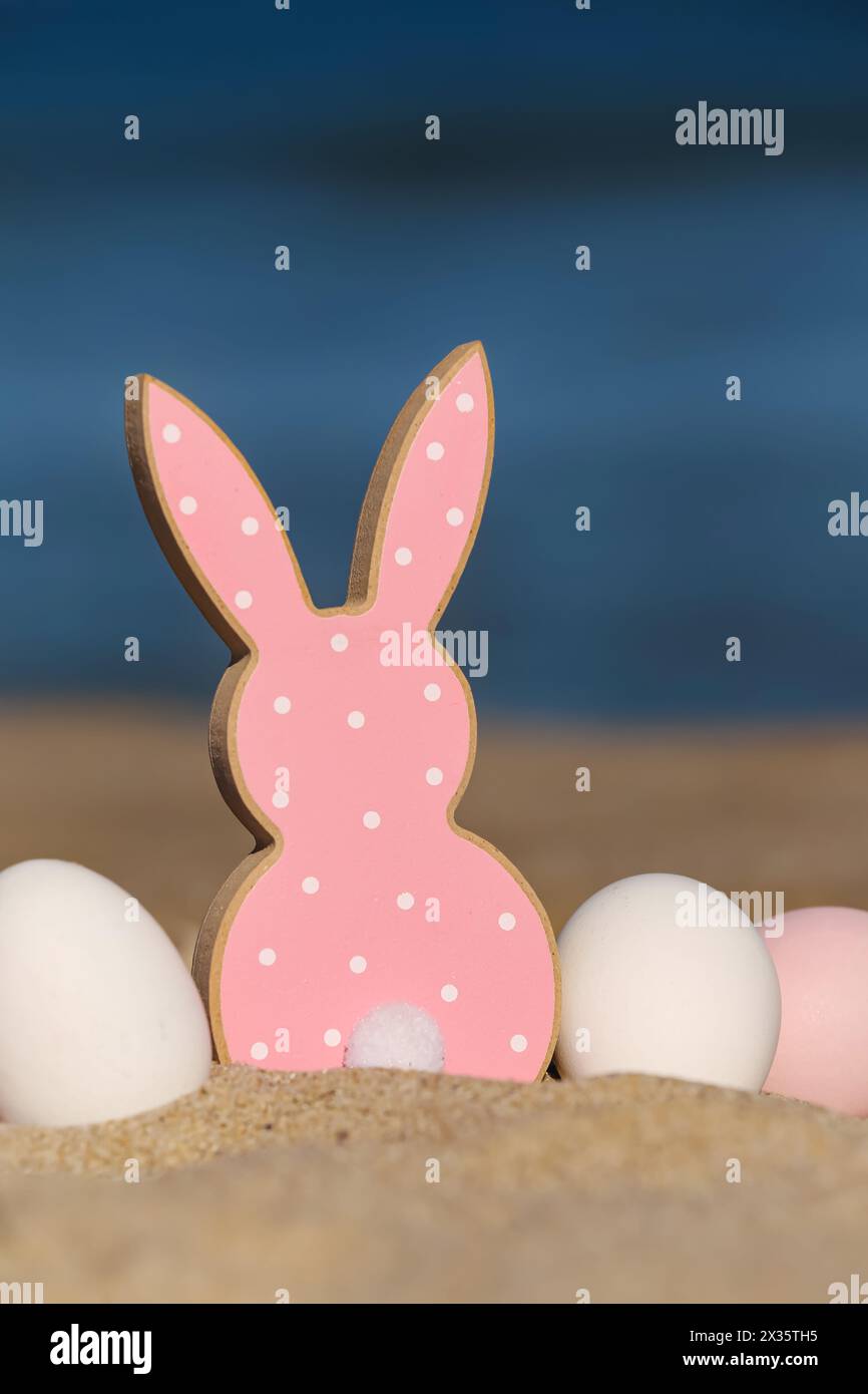 Painted Easter eggs and cookie in shape of bunny on sea beach Stock Photo