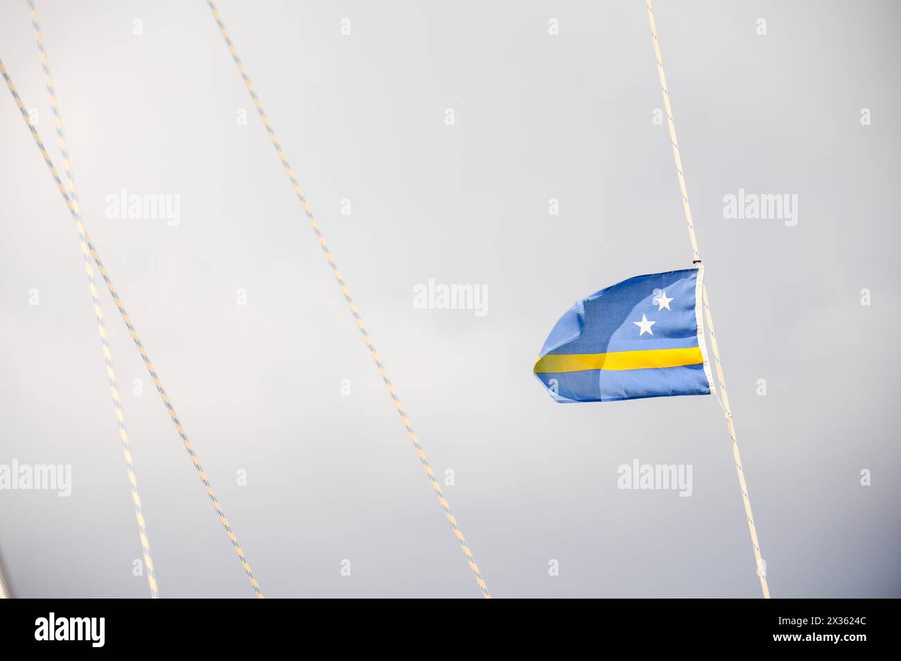 A blue and yellow flag with stars is hanging from a rope. The flag is slightly torn and has a star on it Stock Photo