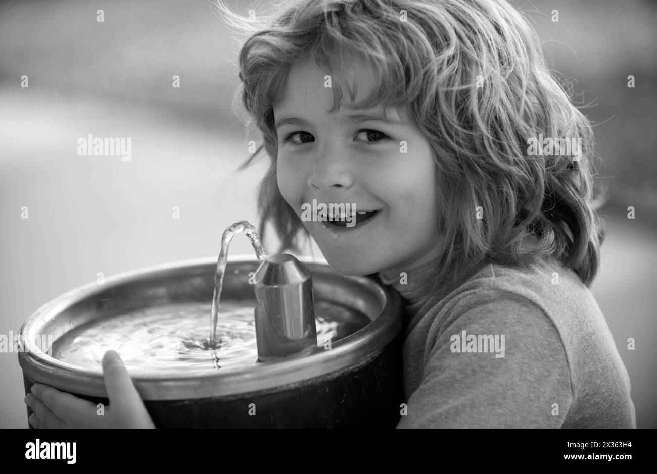 Face close up portrait of kid drinking water from outdoor water fountain outdoor. Stock Photo