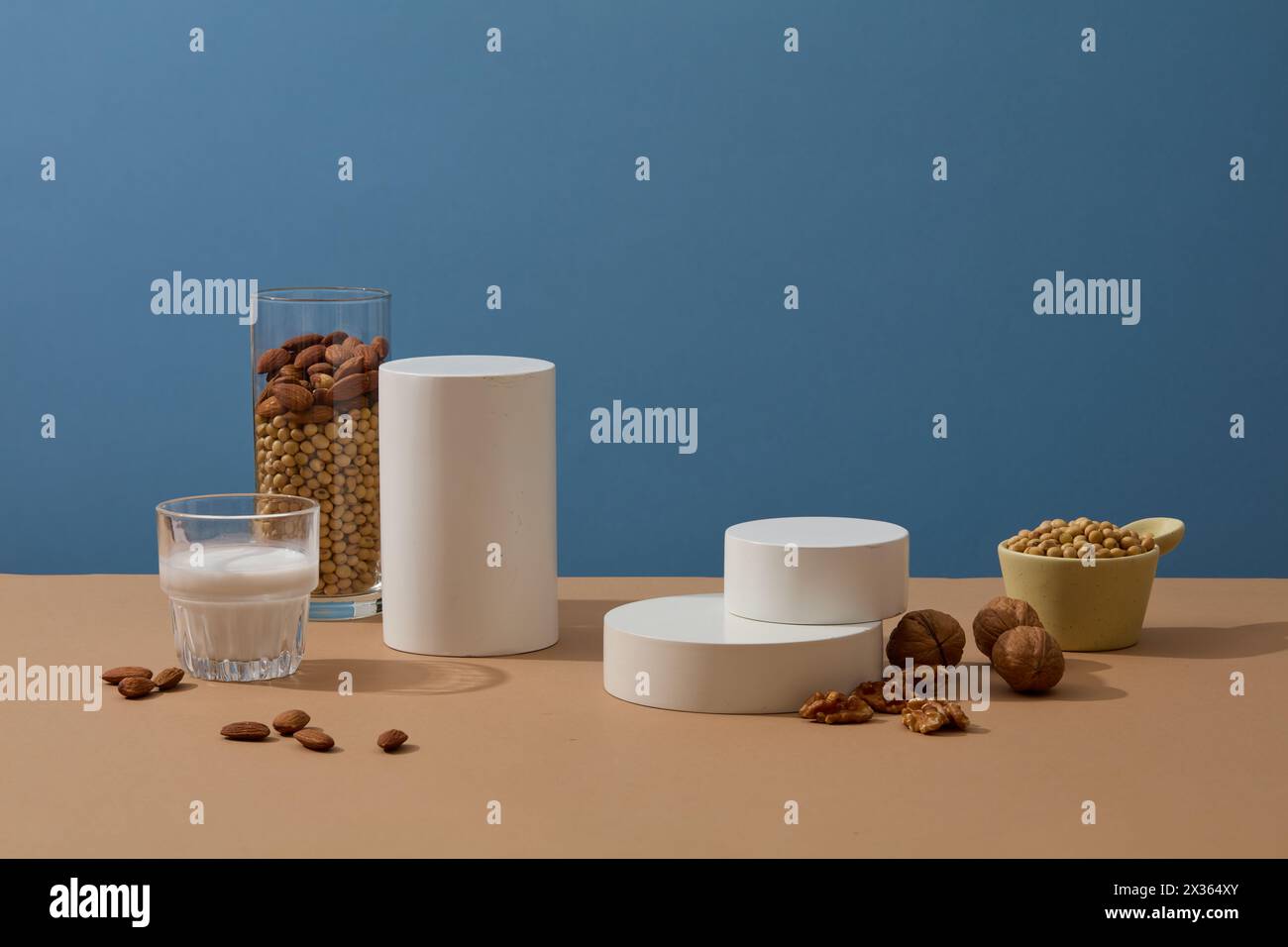 Minimal scene with geometric shaped podiums displayed with a cup of milk, a bowl of soybeans, almonds and walnuts. Stage showcase on pedestal display Stock Photo