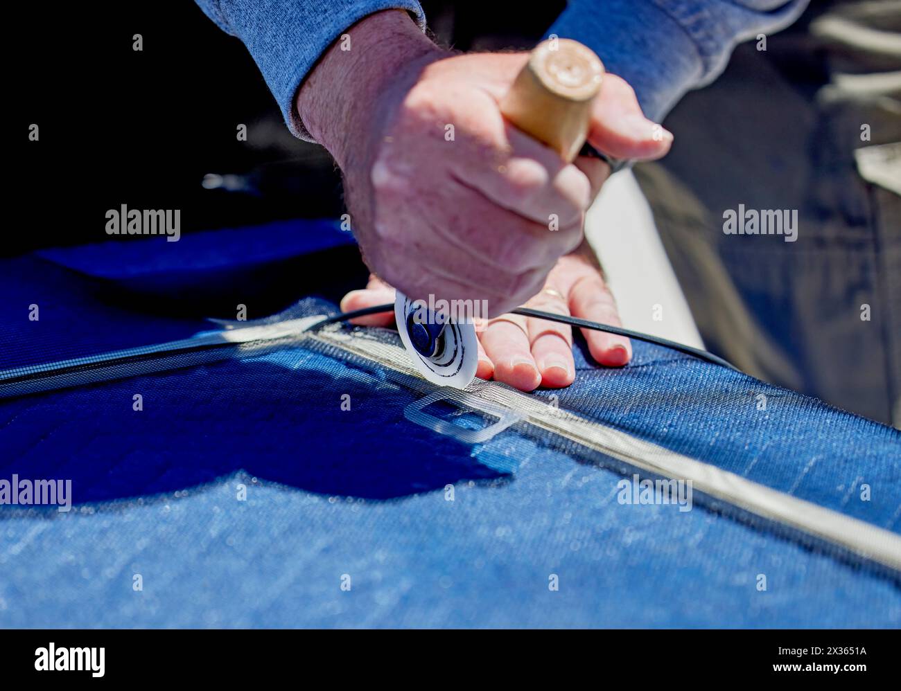 Close up the hands of a man holding a screen roller replacing a window screen into a window frame Stock Photo