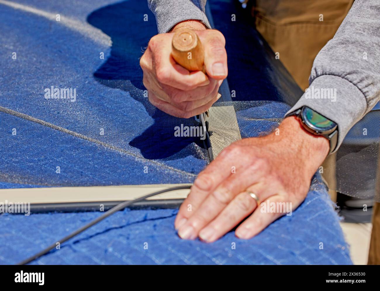 Close up the hands of a man holding a screen roller replacing a window screen into a window frame Stock Photo