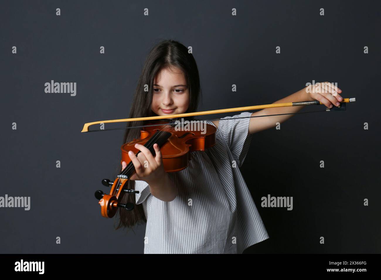 Preteen girl playing violin on black background Stock Photo