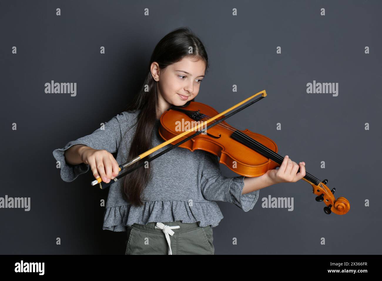 Preteen girl playing violin on black background Stock Photo - Alamy