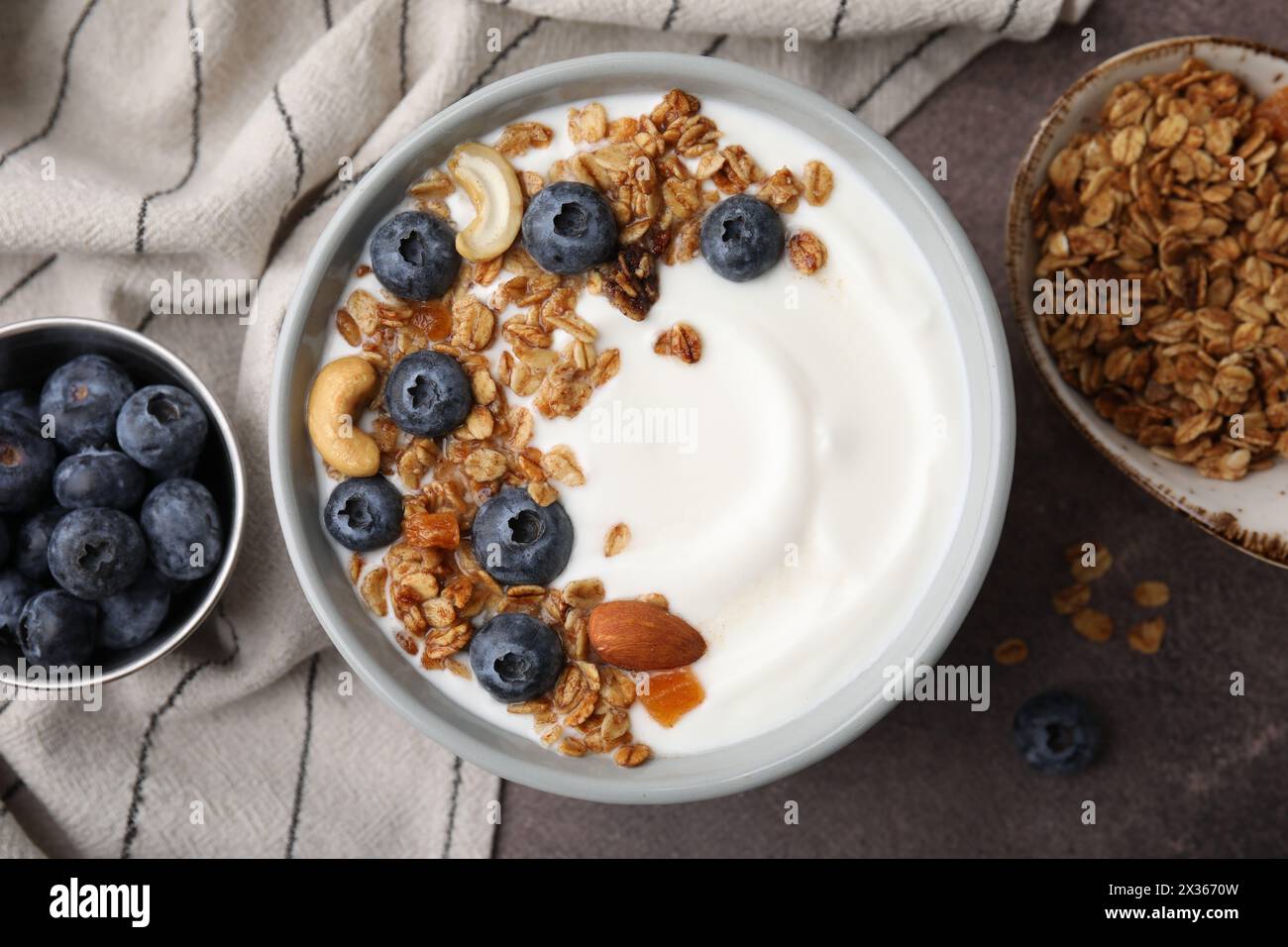 Bowl with yogurt, blueberries and granola on grey table, top view Stock Photo