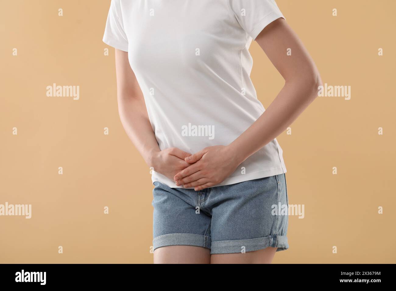 Woman suffering from cystitis on beige background, closeup Stock Photo