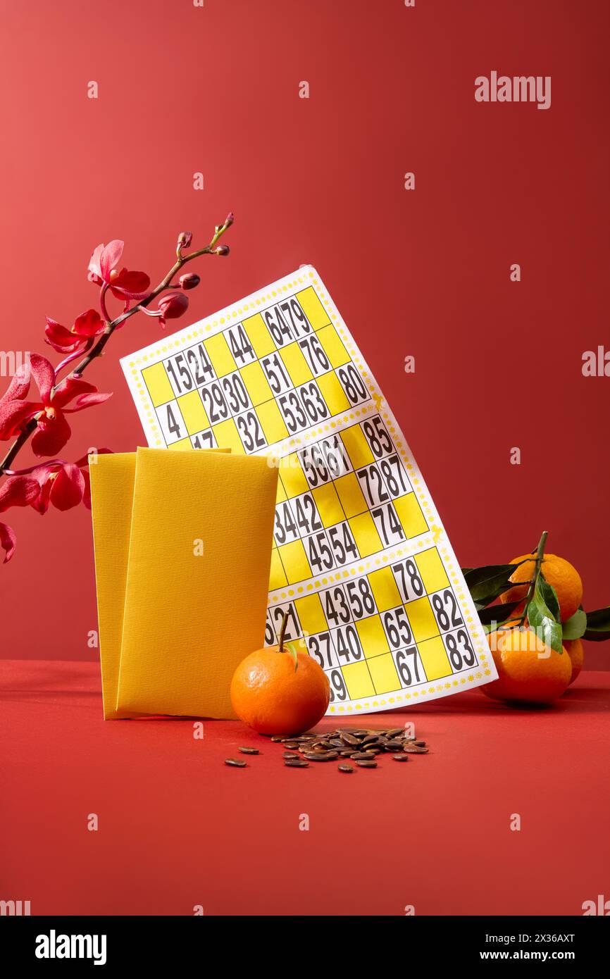 A bingo card decorated with tangerines and yellow envelopes. A pile of melon seeds displayed. Lunar New Year is a time for family reunions Stock Photo