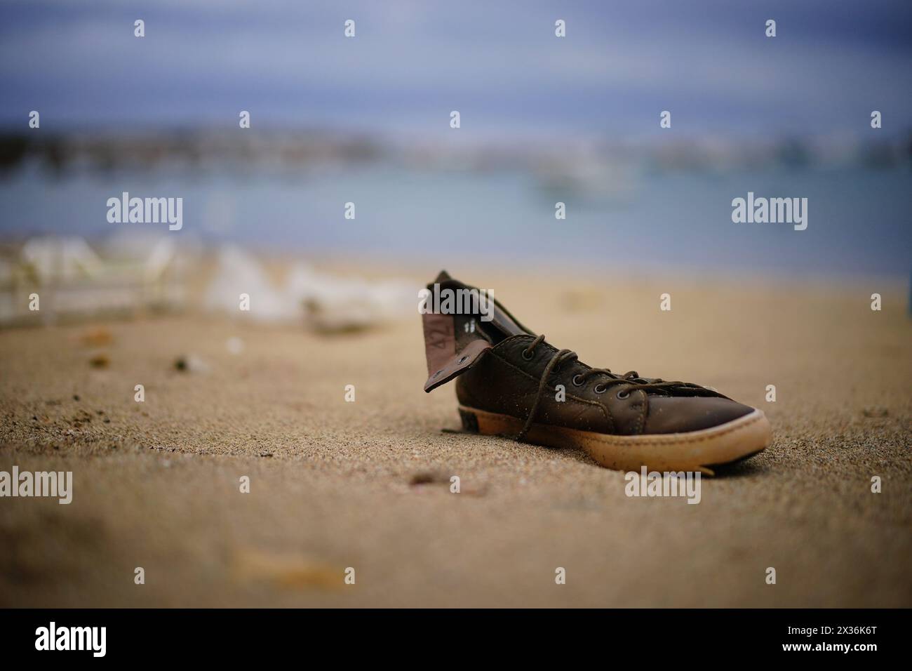 A shoe washed up on a beach next to discarded migrant vessels in Lampedusa, Italy. Picture date: Wednesday April 24, 2024. Stock Photo