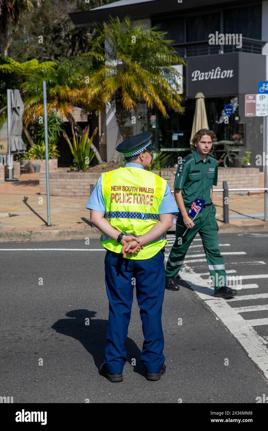 Male NSW Police Officer and St John ambulance officer, police office his directing traffic during Avalon Beach ANZAC Day parade, Sydney,Australia Stock Photo