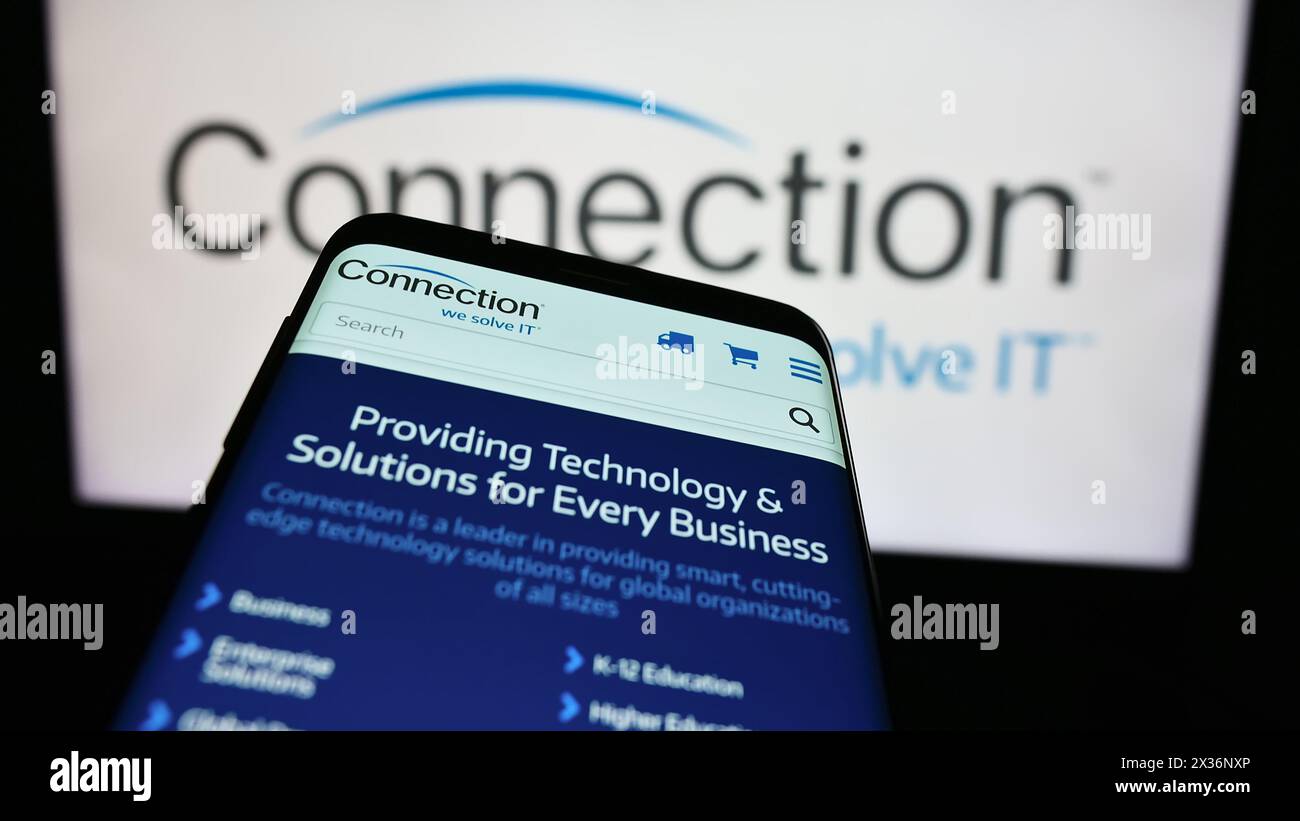 Smartphone with website of US information technology company PC Connection Inc. in front of business logo. Focus on top-left of phone display. Stock Photo