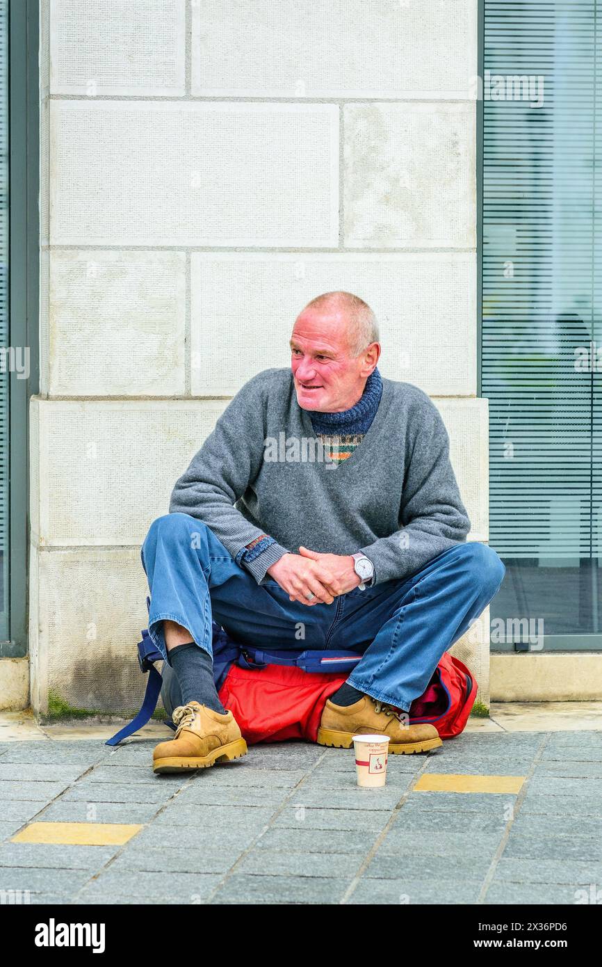 Middle-aged man sitting on city street corner begging for money - Tours, Indre-et-Loire (37), France. Stock Photo