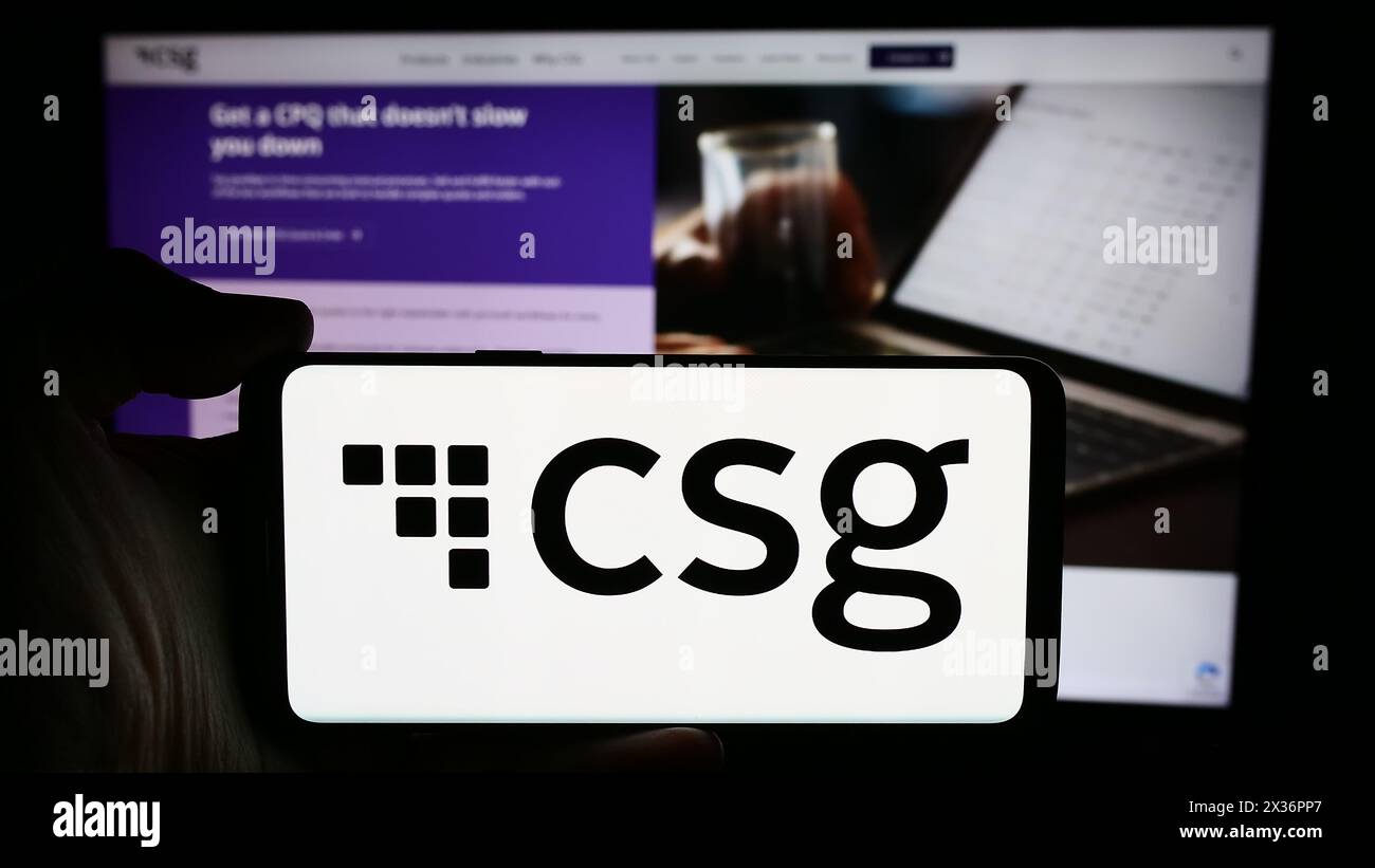 Person holding cellphone with logo of US BSS software company CSG Systems Inc. in front of business webpage. Focus on phone display. Stock Photo