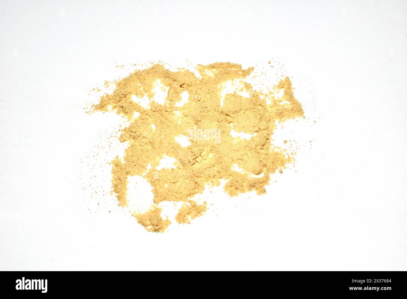 Ground ginger spice is scattered on a white background and is used in cooking. Stock Photo