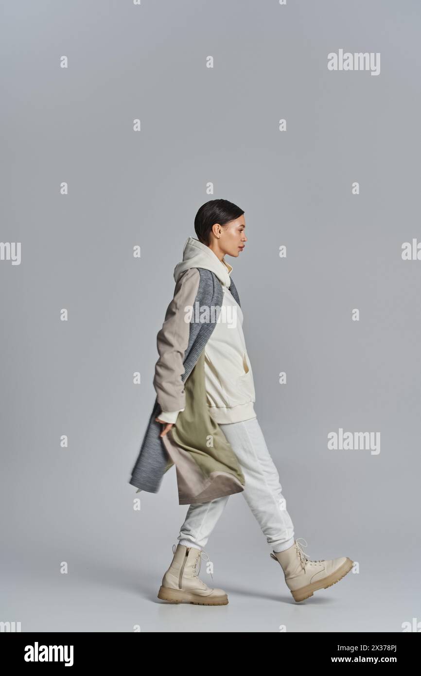 A young stylish woman walks confidently wearing a trench coat in a ...