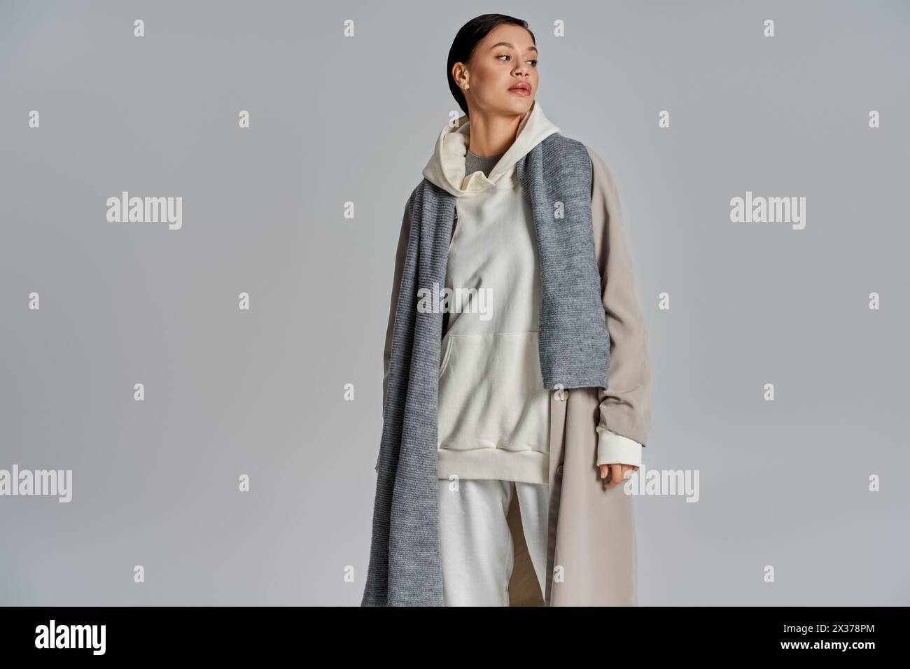 A stylish young woman stands confidently in a trench coat against a ...