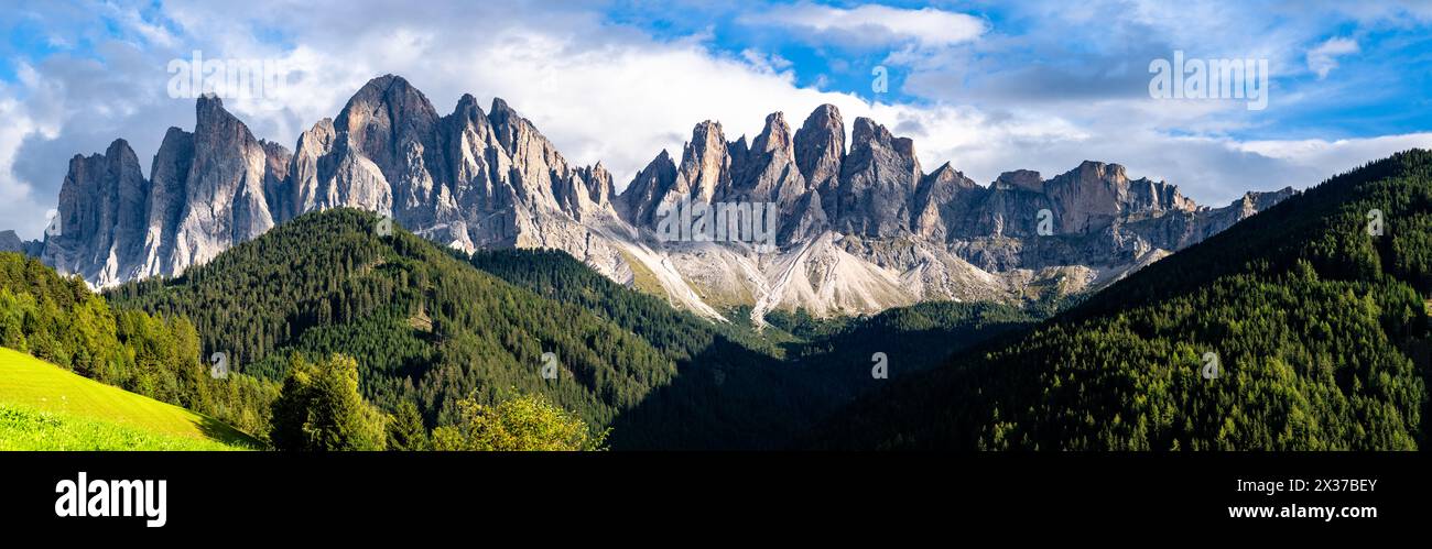 Breathtaking Panoramic View of Green Alpine Meadows with Majestic Rocky Mountains, Clear Blue Sky, and Lush Forests in Dolomites, Italy. Stock Photo