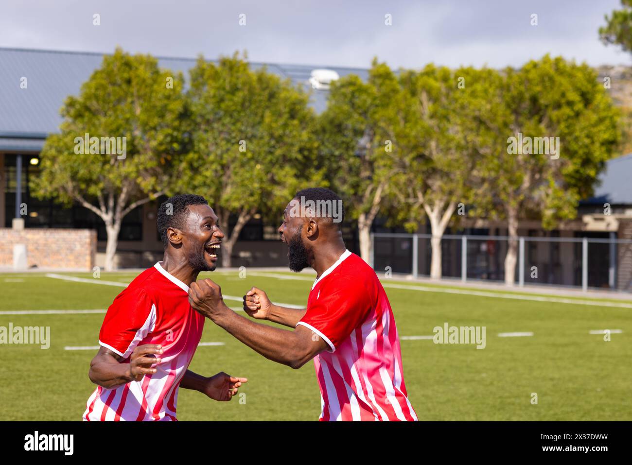 Two African American young male athletes are celebrating on field outdoors Stock Photo