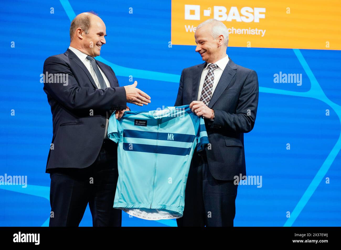 Mannheim, Germany. 25th Apr, 2024. Martin Brudermüller (l), Chairman of the Board of Executive Directors of BASF SE, hands over a cycling jersey to Markus Kamieth, future Chairman of the Board of Executive Directors of BASF SE, at the Annual Meeting of the chemical company BASF. It is the last shareholders' meeting of Chairman Brudermüller. Kamieth will take office at the end of the Annual Meeting. Credit: Uwe Anspach/dpa/Alamy Live News Stock Photo