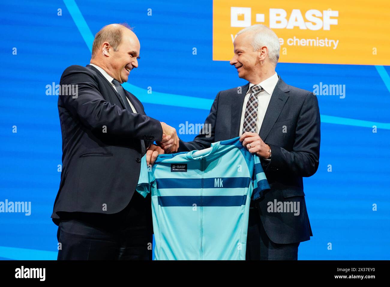 Mannheim, Germany. 25th Apr, 2024. Martin Brudermüller (l), Chairman of the Board of Executive Directors of BASF SE, hands over a cycling jersey to Markus Kamieth, future Chairman of the Board of Executive Directors of BASF SE, at the Annual Meeting of the chemical company BASF. It is the last shareholders' meeting of Chairman Brudermüller. Kamieth will take office at the end of the Annual Meeting. Credit: Uwe Anspach/dpa/Alamy Live News Stock Photo