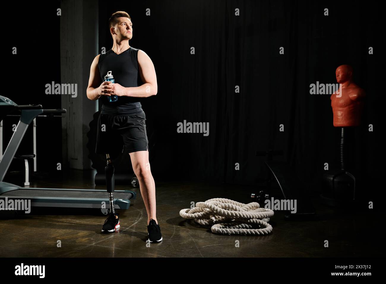 A man with a prosthetic leg stands confidently in front of gym equipment, showcasing determination and resilience in his workout routine. Stock Photo