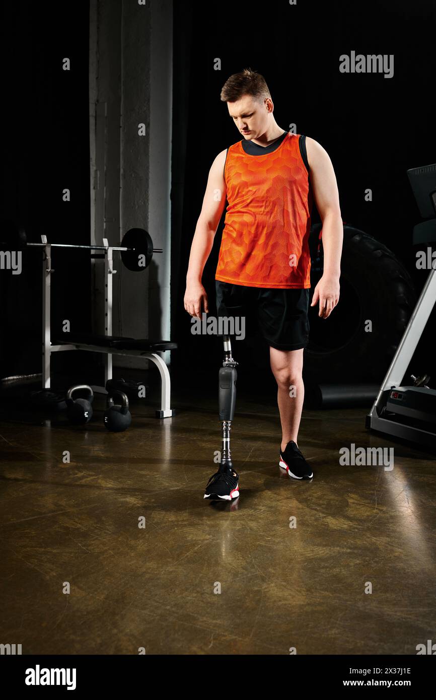 A man with a prosthetic leg, standing in a gym surrounded by exercise equipment. Stock Photo