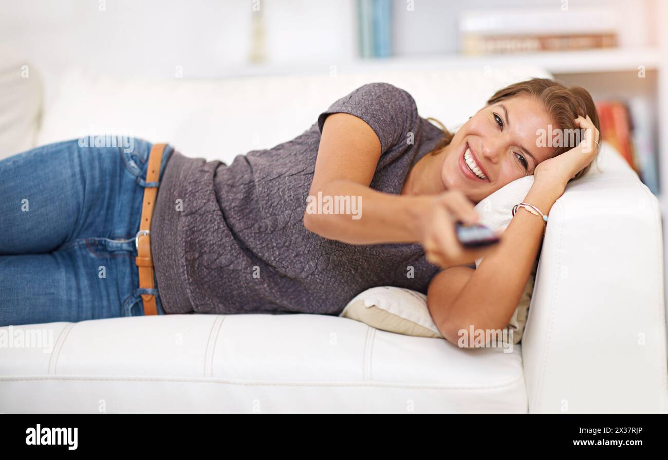 Woman, sofa and tv with remote and relax in home, popcorn and watching on weekend. Holiday, laugh and comedy movie or show, streaming videos and couch Stock Photo