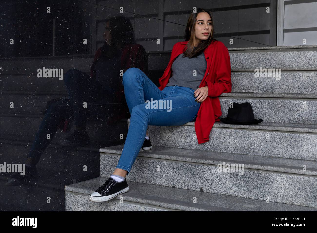 Portrait of young Latin American woman sitting on stairs. Poses with ...