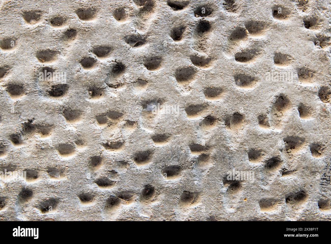 Gray structural stone wall of the ancient building consists of old structural plaster. Stock Photo