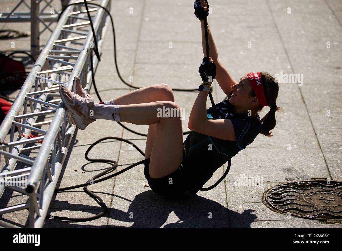 Young female pulls the rope with heavy weight on a Hercules hoist at