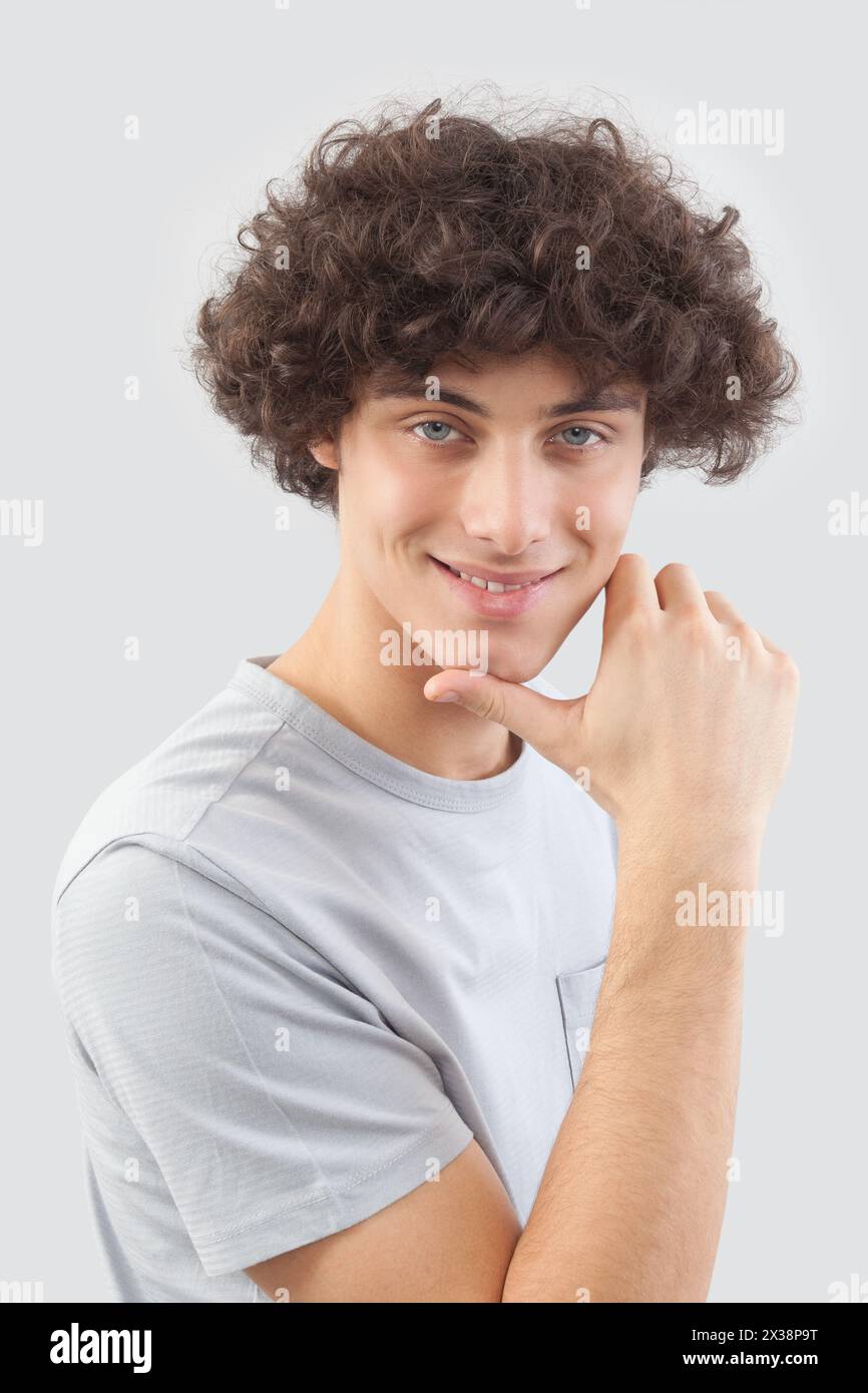 Smiling and handsome a young man with curly hair he looks into the ...