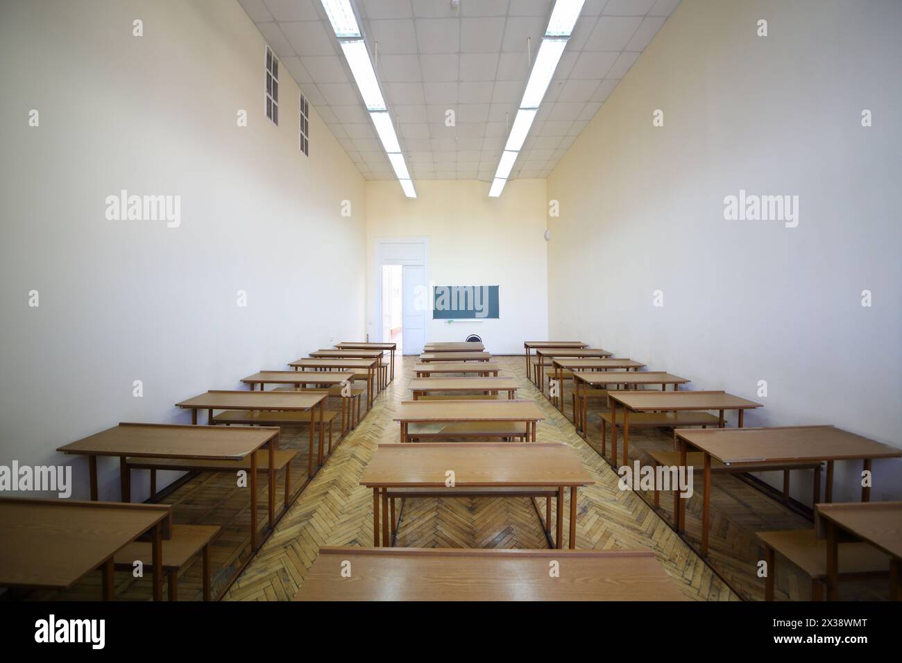 Empty classroom with rows of wooden tables for students and chalkboard ...