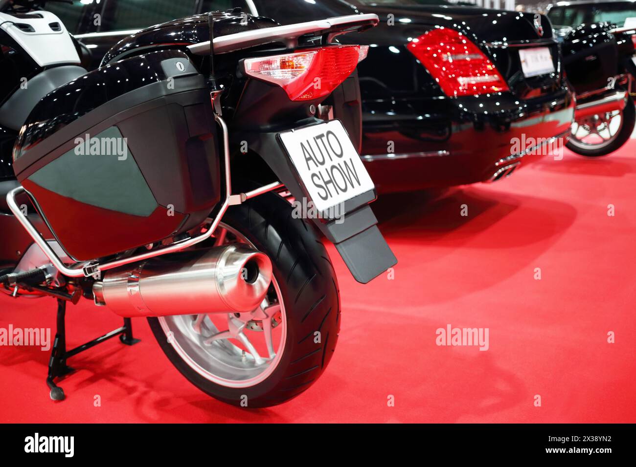 Black shiny bike for cortege, car are on red carpet in exhibition, back view Stock Photo