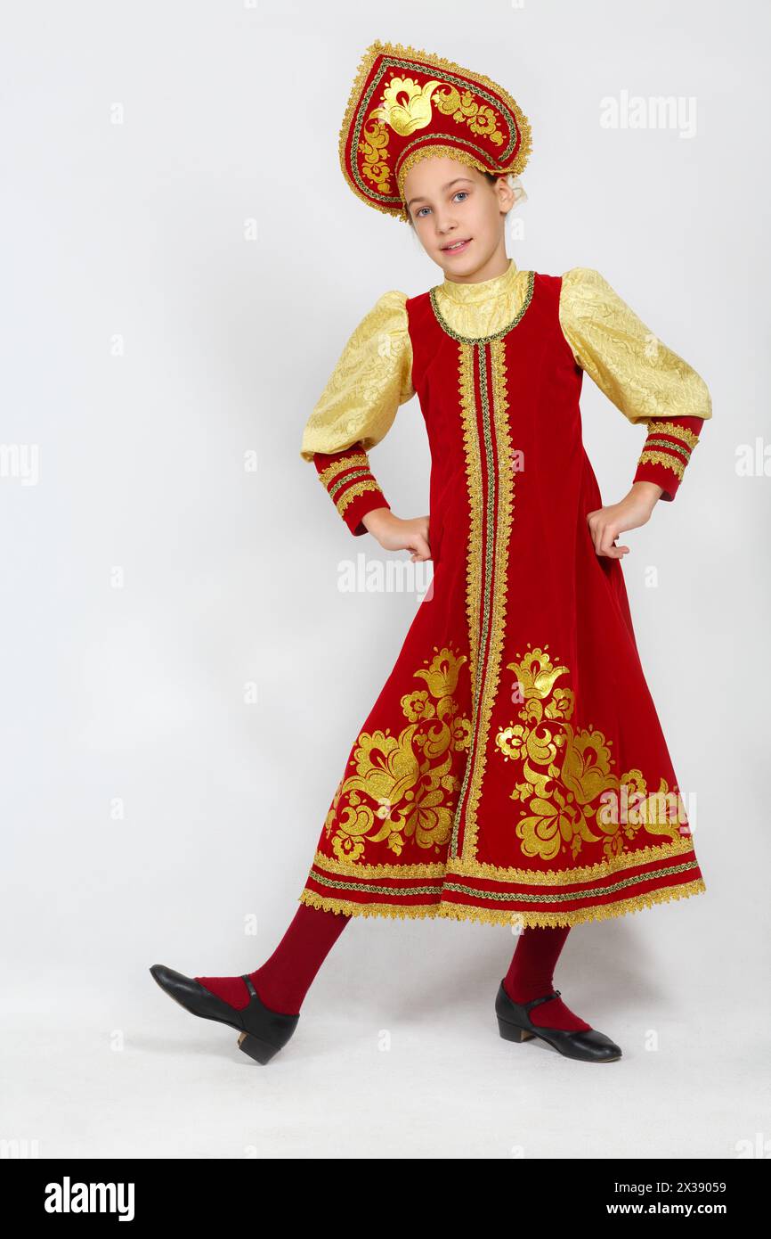 Pretty girl in red russian folk costume dances in white studio Stock