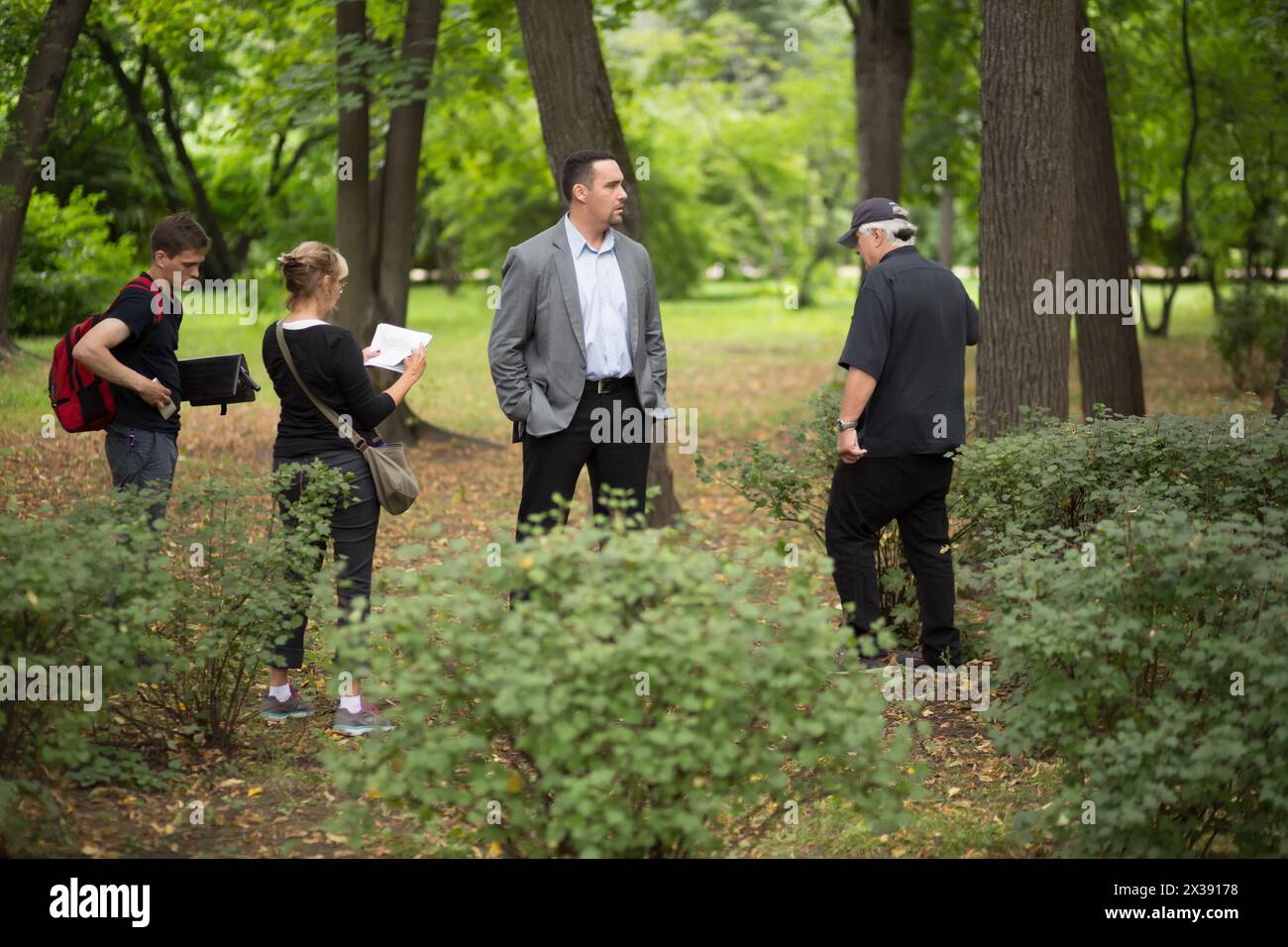 RUSSIA, MOSCOW - 30 JUL, 2015: Actor Alexander Nevsky with assistant are standing in the Sokolniki park at shooting movie (Maximum shock). Stock Photo