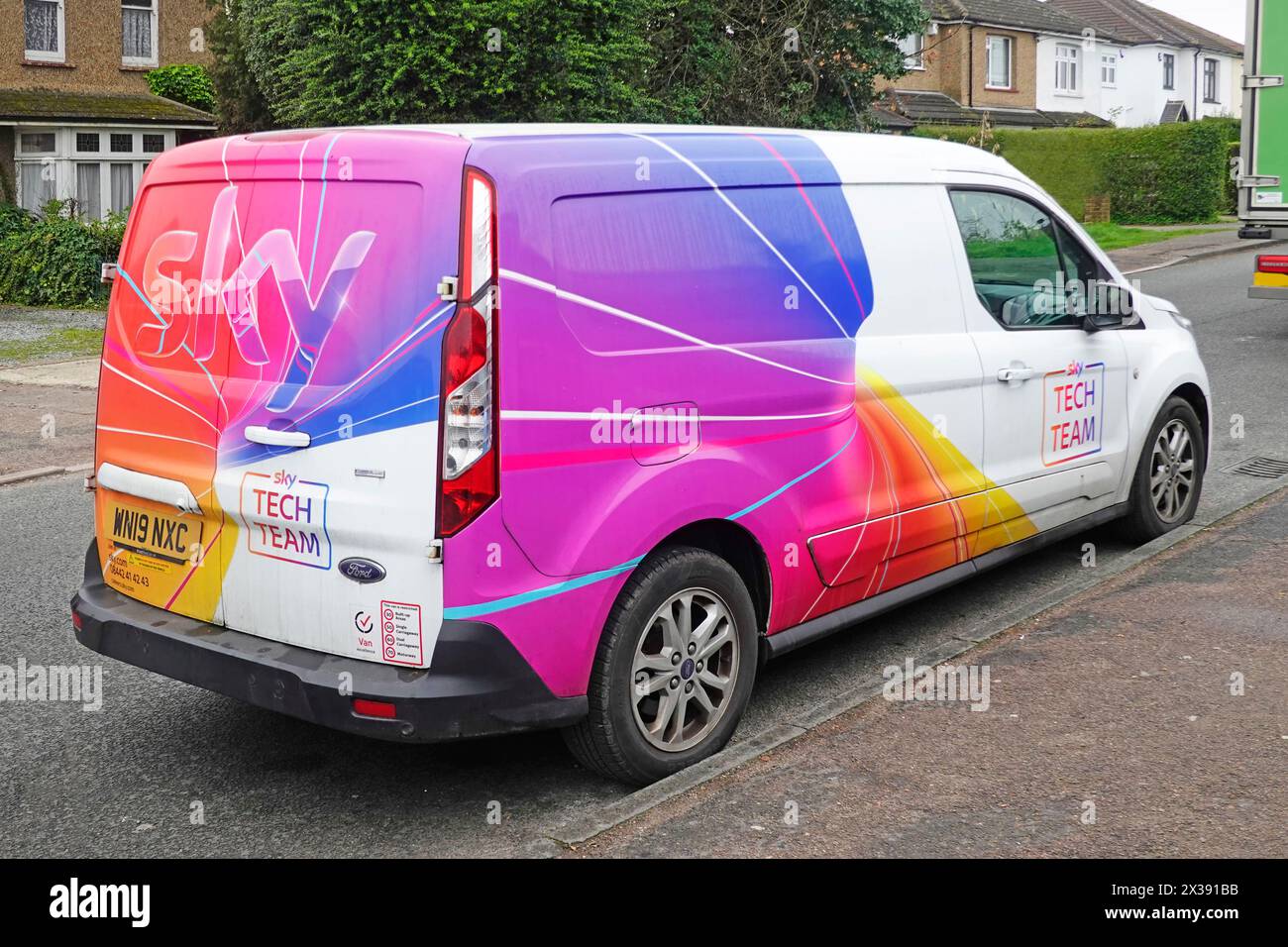 Sky Television Tech Team Ford van eye catching colourful graphics side & back view parked outside homes residential street Brentwood Essex England UK Stock Photo