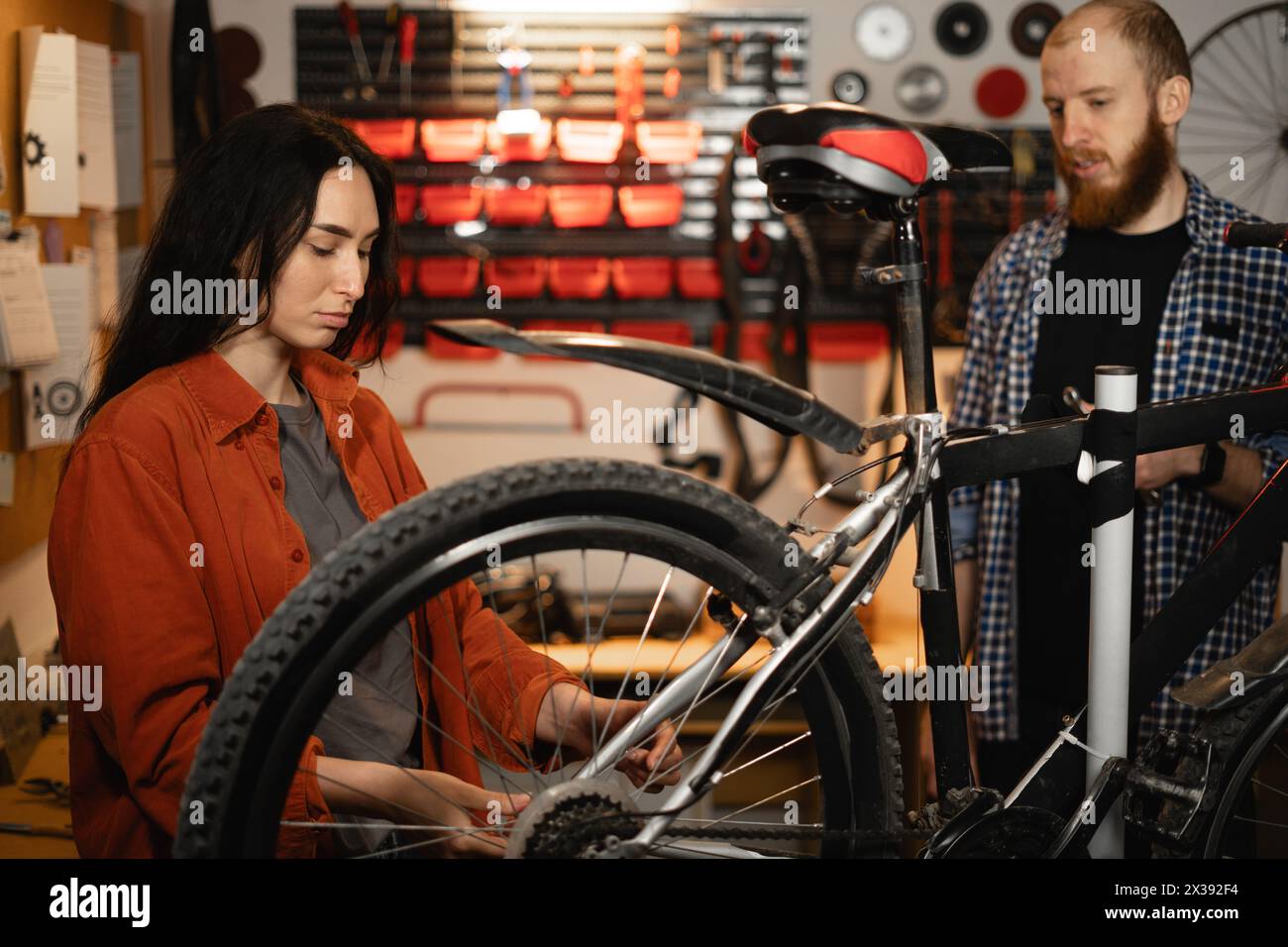 Bike service, repair and upgrade concept. Repairman couple or colleagues fixing bicycle in garage. Stock Photo