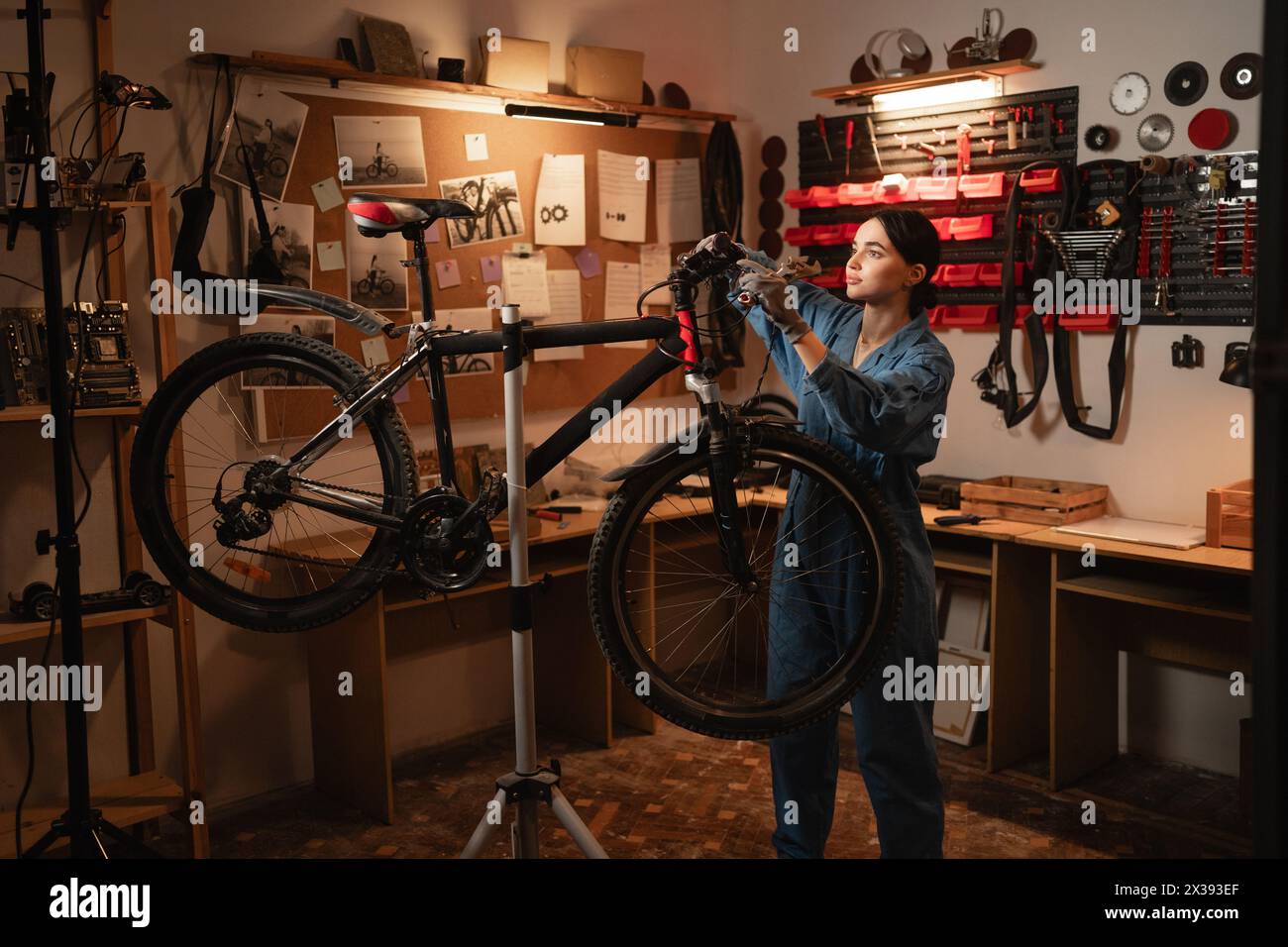 Bicycle female mechanic repairing bicycle doing his professional work in workshop or garage. Stock Photo