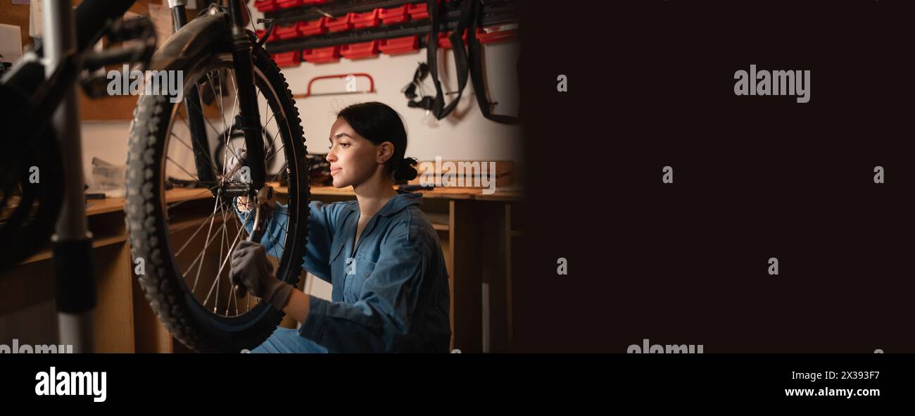 Bicycle female mechanic repairing bicycle doing his professional work in workshop or garage. Stock Photo