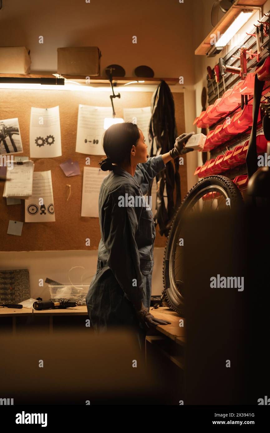 Female bicycle mechanic working in a garage. Bicycle repair and upgrade concept. vintage repair workshop style Stock Photo